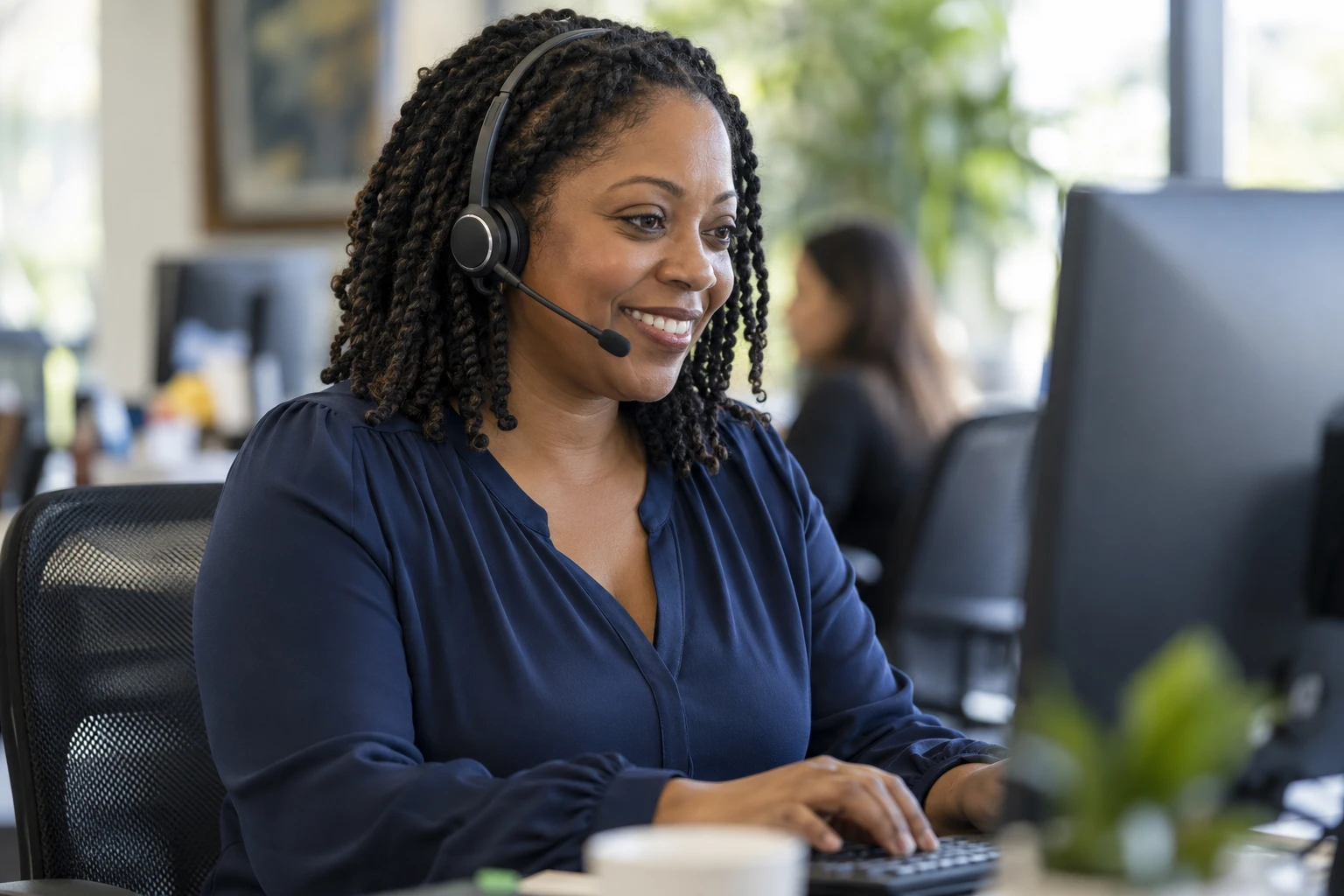 Smiling Joint Heirs contact center agent wearing a headset at her desk